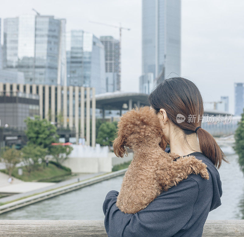 一个女人抱着她的宠物站在桥上看风景