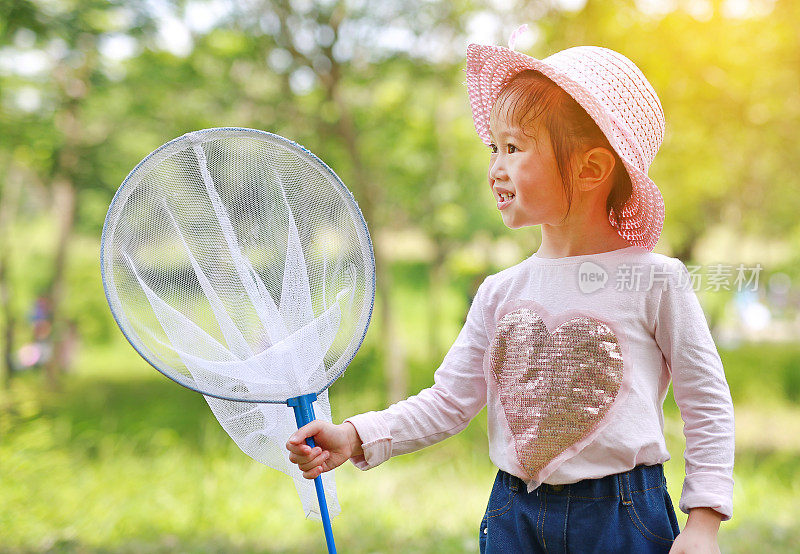 可爱的亚洲小女孩戴着草帽和蚊帐在田野里玩夏天。