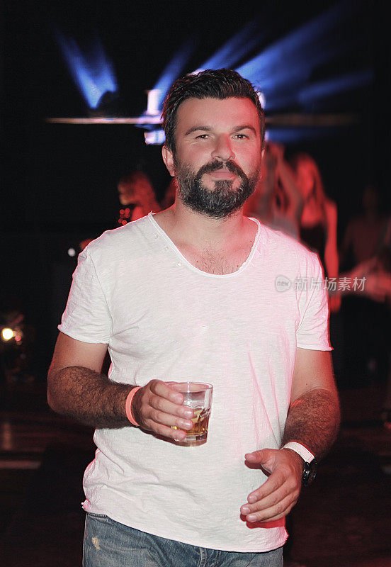 一个微笑的男人在夜店喝着威士忌的肖像