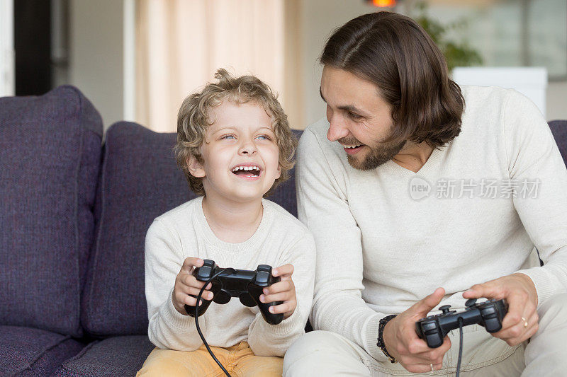 父亲玩电子游戏，儿子玩得很开心