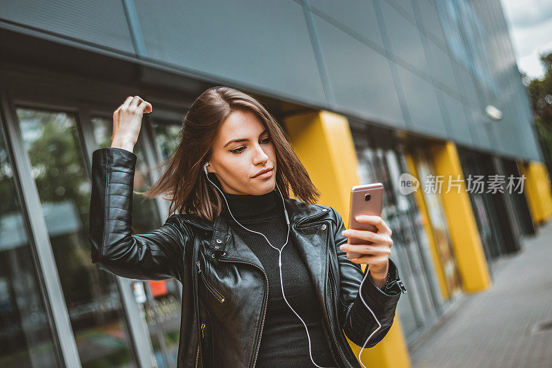 美丽的女人在城市街道上的手机