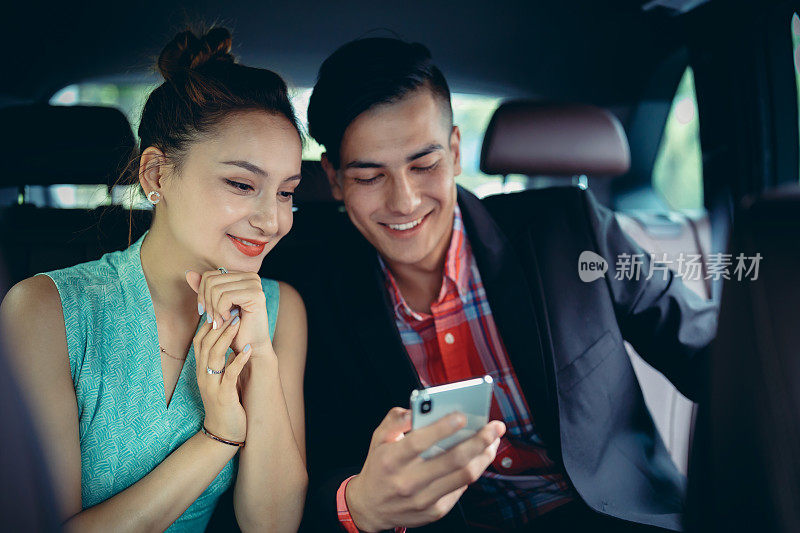 商人和女商人在汽车后座上使用智能手机。