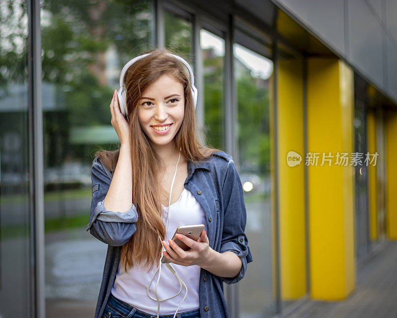 在城市街道上听音乐的美丽女人