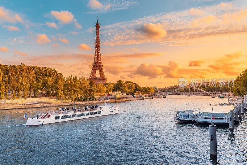 巴黎和整个欧洲的主要景点是落日余晖中的埃菲尔铁塔和游船停靠在塞纳河岸边