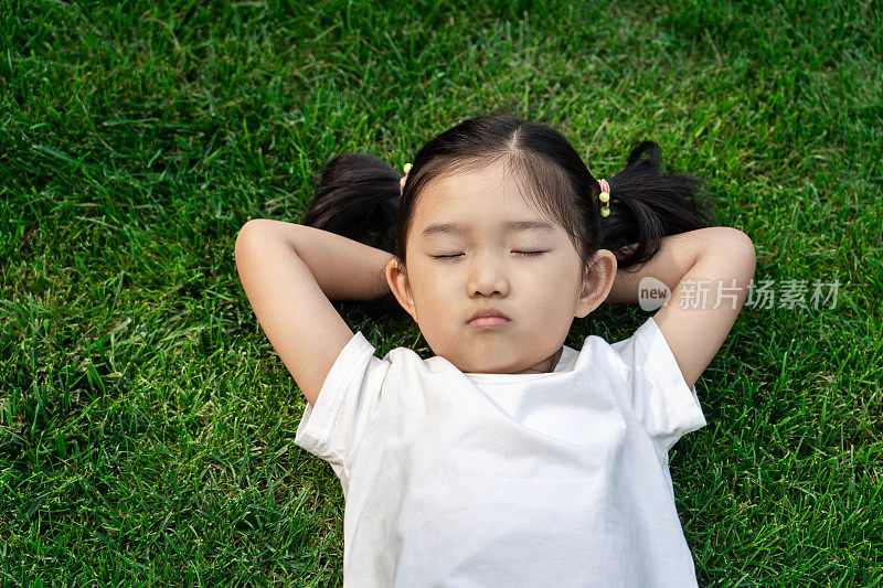可爱的女孩躺在草坪上