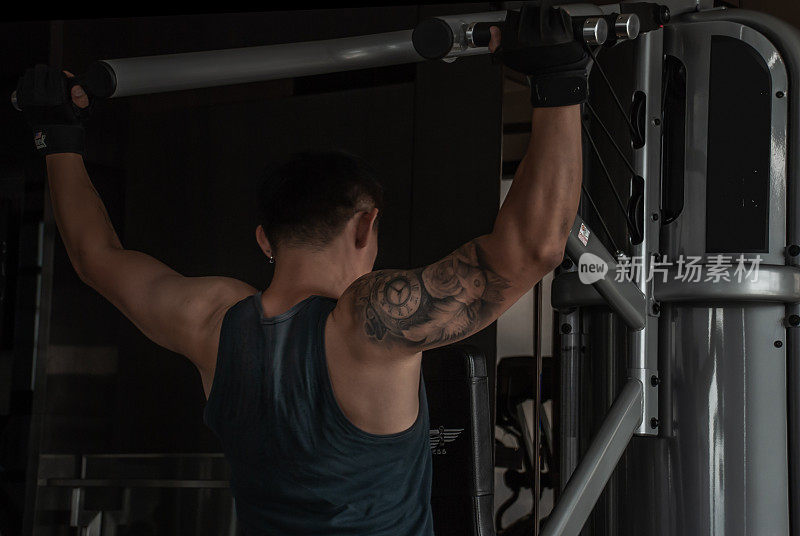 在健身房或健身俱乐部，健身者的背部在锻炼机上举重。