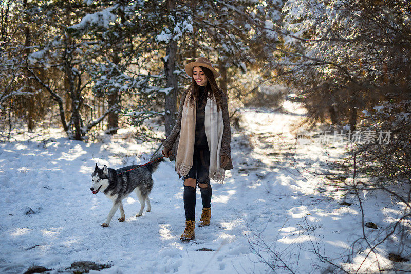 带着狗在雪地上散步的女士