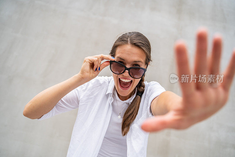 快乐的年轻女人的肖像与太阳镜在户外挥舞