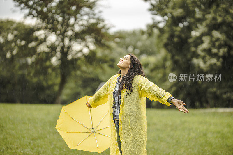 拿着黄伞，穿着黄雨衣，享受着雨的女人