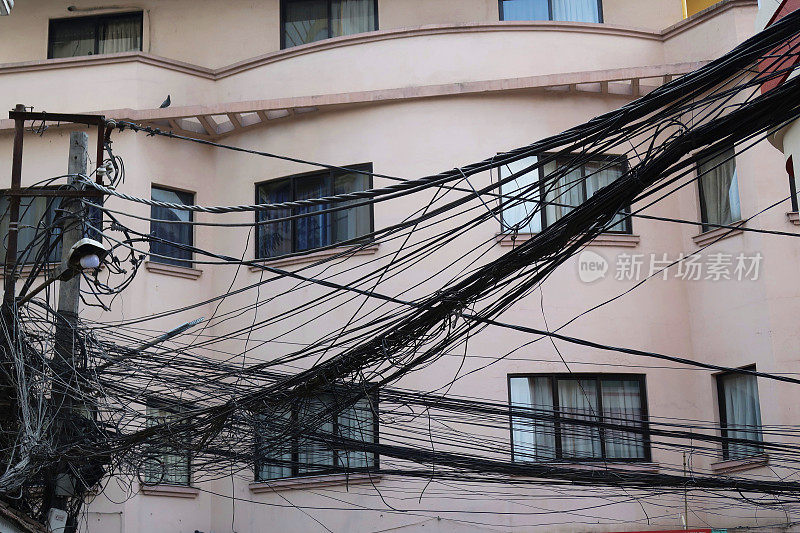 印度德里街头电线塔之间缠绕的画面，建筑物前危险的电线