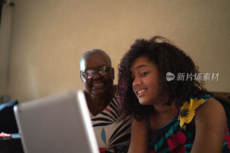 祖母和孙女正在用家里的平板电脑进行视频通话