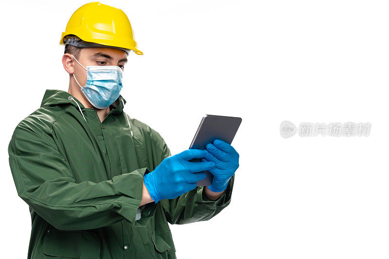 年轻工程师或工人戴着N95口罩和手术手套，在白色背景上使用数码平板电脑