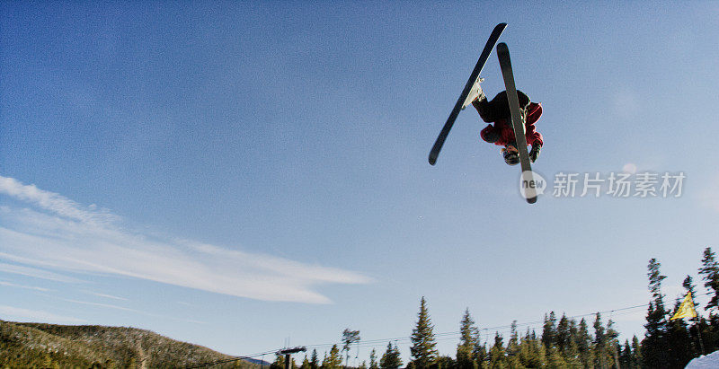 在科罗拉多州博尔德附近的埃尔多拉滑雪度假村，一个滑雪者在一个多雪的阴天，在森林和滑雪缆车的背景下尝试一个“左360”跳魔术