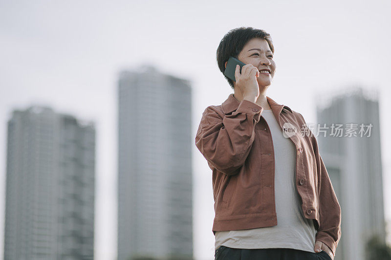 亚洲华人中年妇女在晚上在户外通过电话交谈微笑