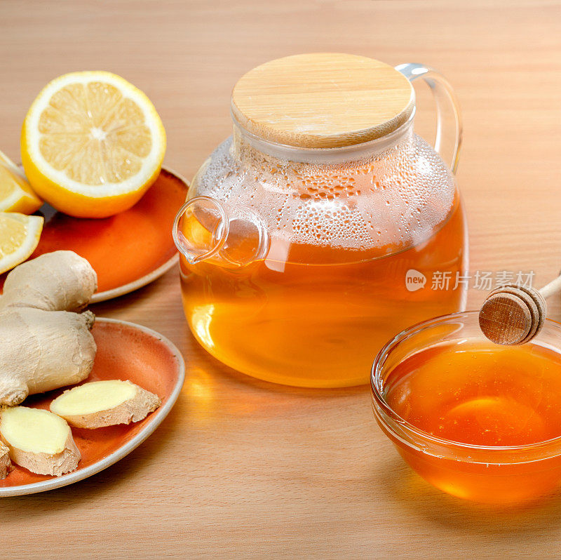 姜茶柠檬和蜂蜜玻璃茶壶在木桌