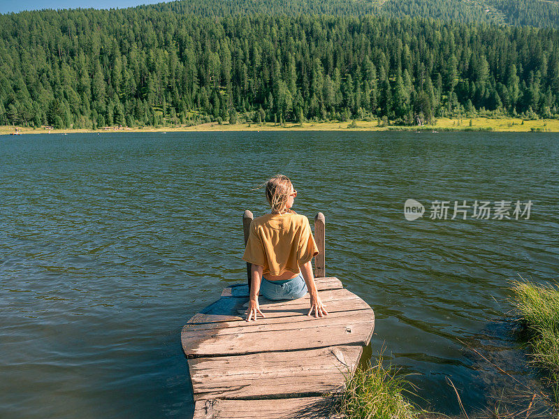 年轻女子在湖边码头休息