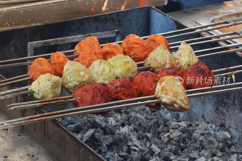 金属烤肉串上烤着的蒸馄饨，一排排地躺在滚烫的炭火上