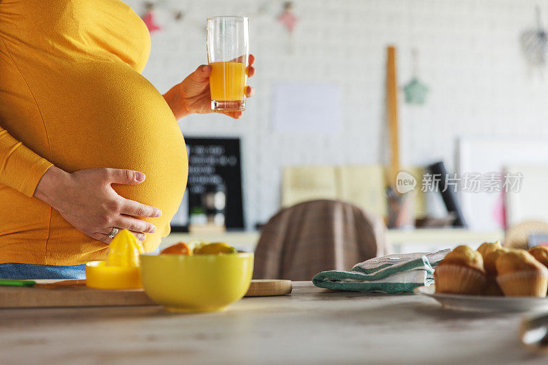 孕妇在喝完爽口的橙汁后抱着怀孕的肚子