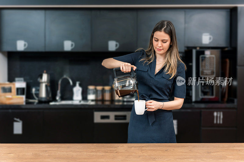 美丽的女商人在现代厨房里装咖啡