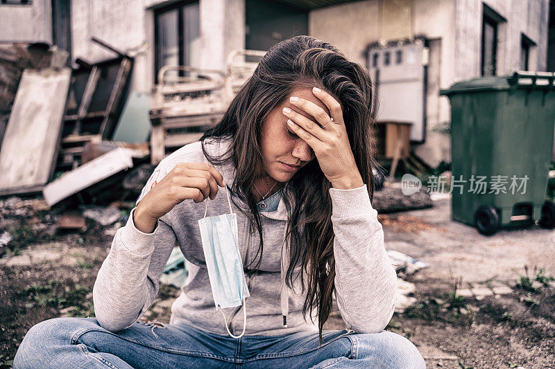 沮丧和疲惫的年轻女人在一只手拿着一个面具