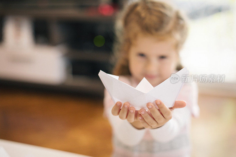 可爱的小女孩用纸制作船