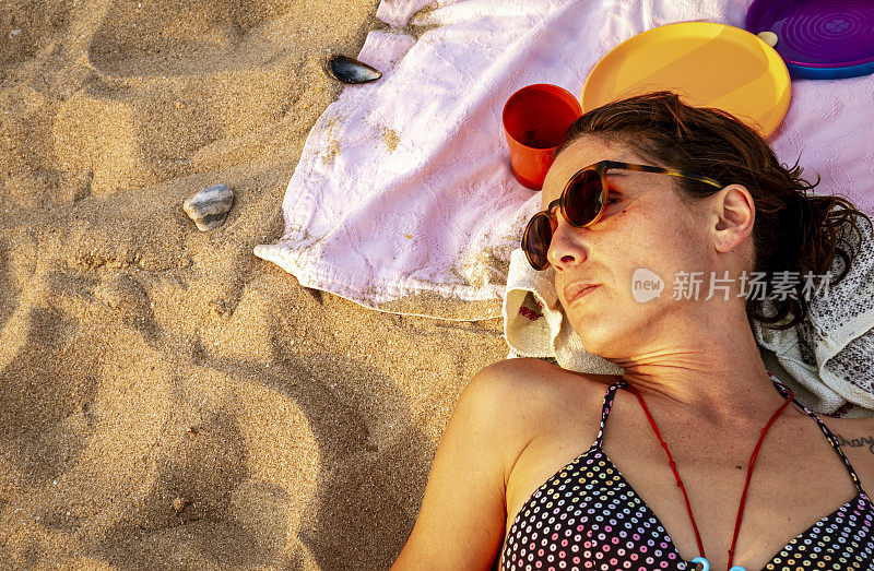 女人躺在沙滩浴巾上晒太阳