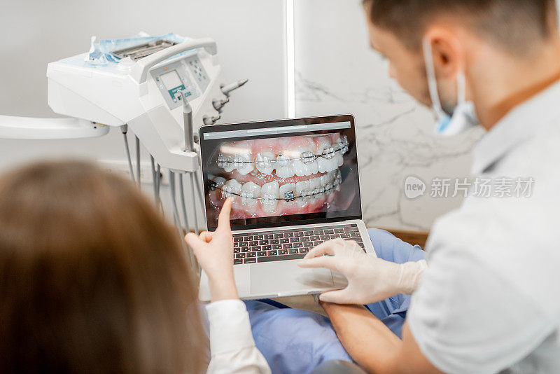 牙医在一个年轻病人的监视器上显示牙齿的照片