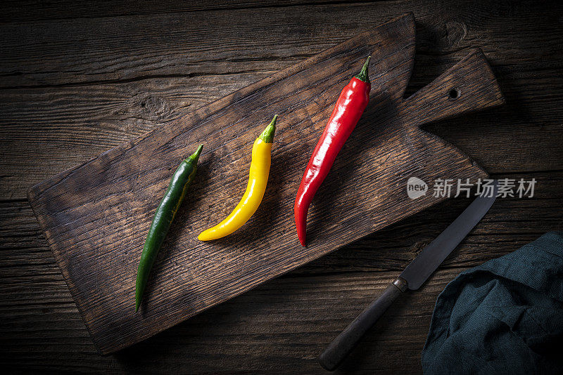搭配三种颜色的红、绿、黄辣椒放在木切菜刀上