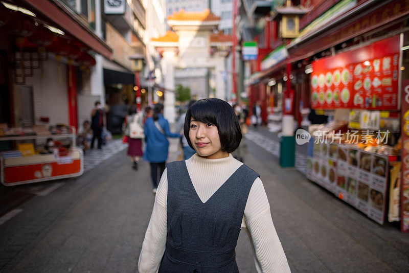 一个年轻的女人走在日本神户唐人街的街道中间