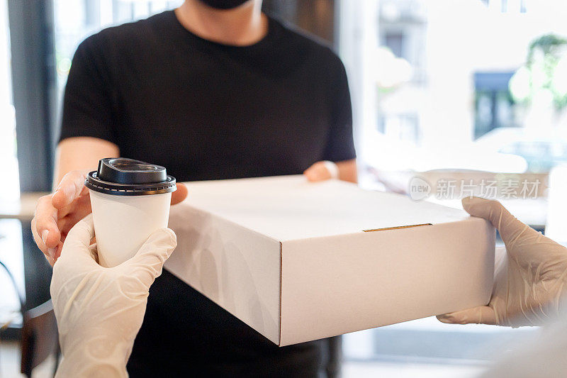 戴上防护手套，将便当盒和用一次性杯子装的咖啡传递给顾客