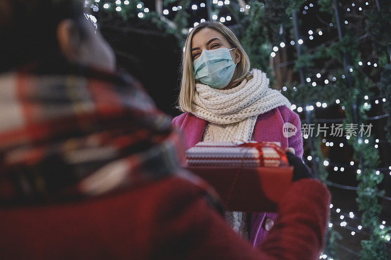 母亲和女儿在保持社交距离的同时交换圣诞礼物