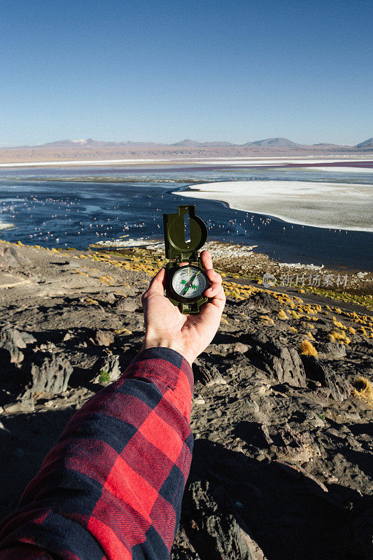 玻利维亚Altiplano，在日落时分，一名男子手持指南针站在科罗拉多州的拉古纳湖前