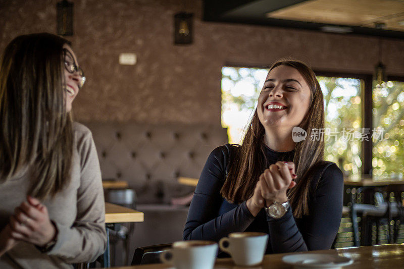 两个开心的女人在咖啡馆里喝咖啡。