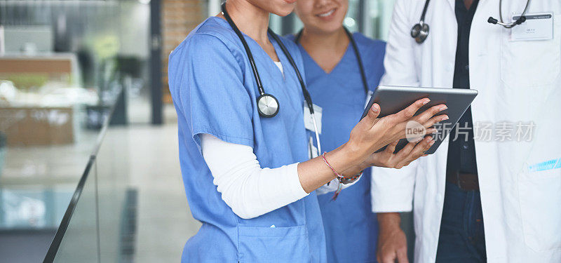 一位面目全非的医生和他的护士们站在一起，用平板电脑进行讨论