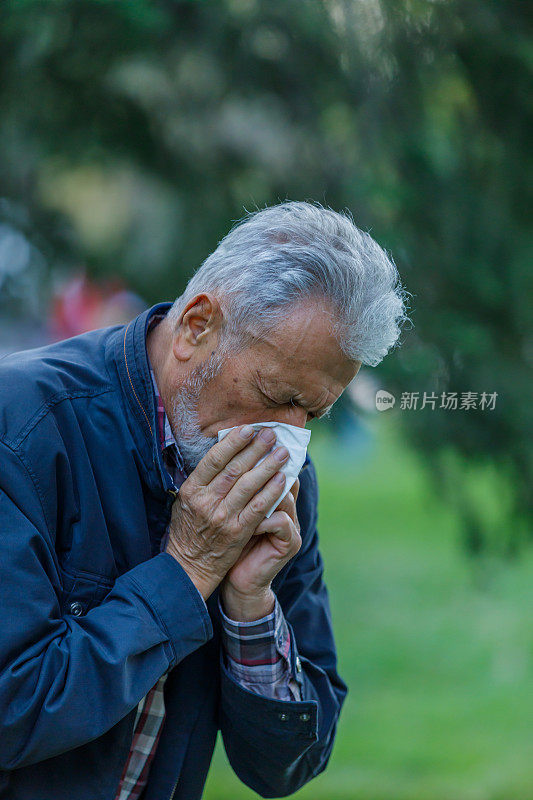 一名患季节性流感的男子在公园里散步，并用纸巾咳嗽。