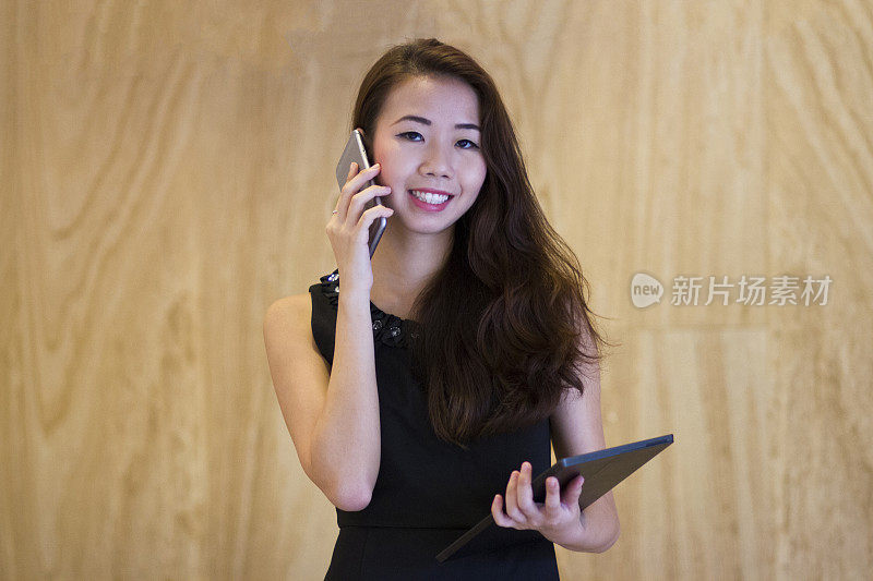 一位年轻迷人的亚洲千禧一代女商人正在使用智能手机和数字平板电脑。