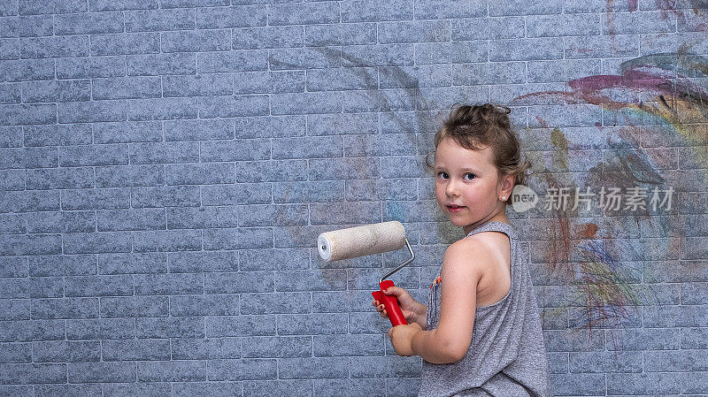 公寓装修，一个六岁的白人女孩拿着油漆滚筒。