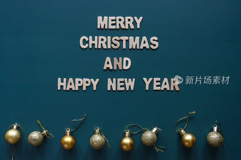 自制DIY简易圣诞卡设计的图像，蓝绿色背景上剪出白色字母，手工制作的圣诞贺卡，圣诞快乐和新年快乐的信息与黄金小饰物
