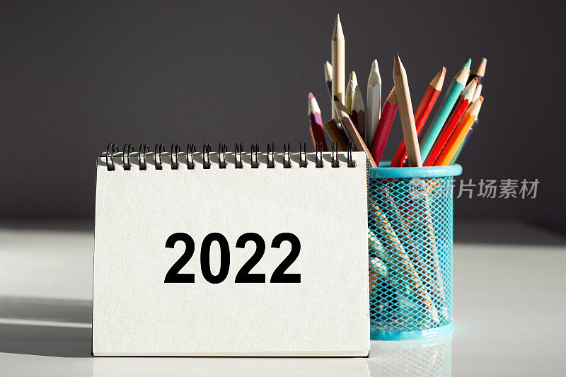 2022文本在灰色背景的记事本和蓝色笔筒