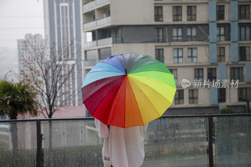 雨点落在彩虹伞上，天以自然为背景