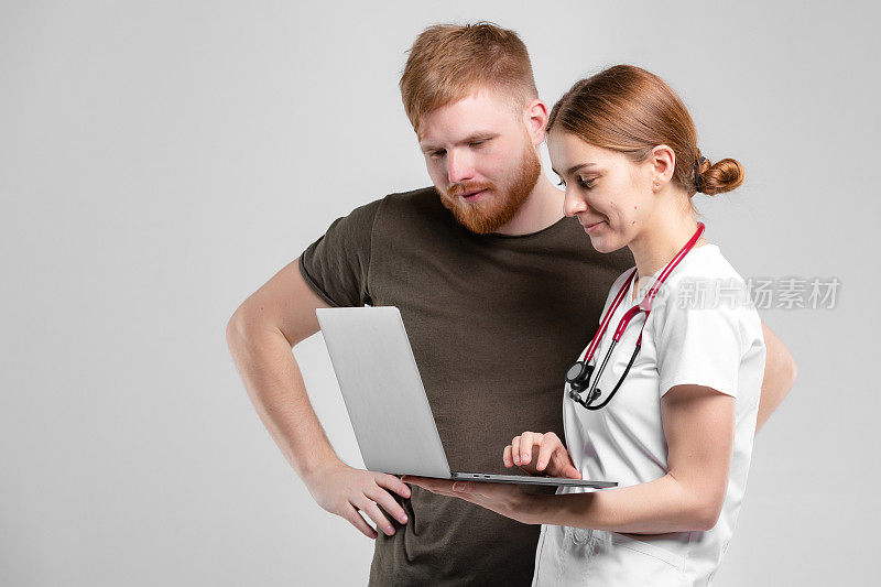 两个人在工作室的肖像，医生和病人。一位女士在笔记本电脑上工作，谈论客户在诊所的医疗测试结果反馈。