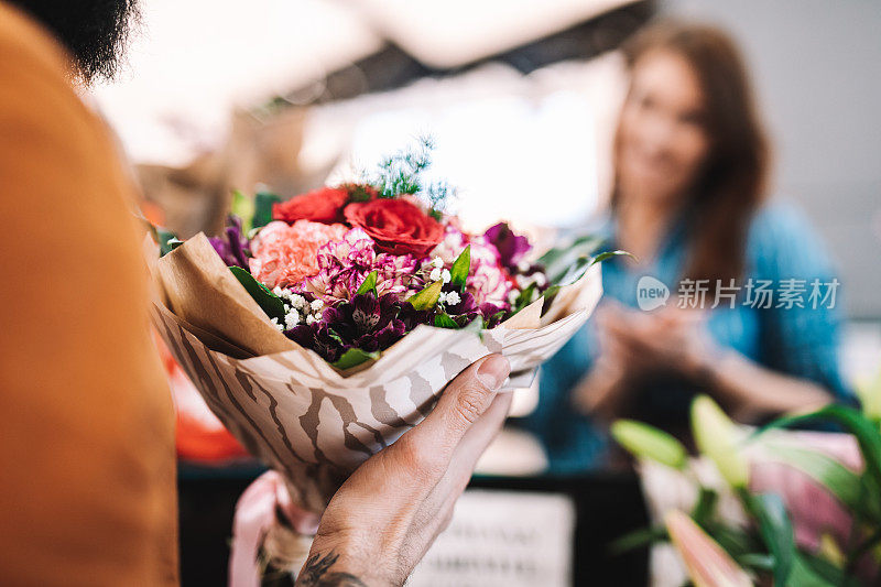 英俊的花商卖花给年轻快乐的女人