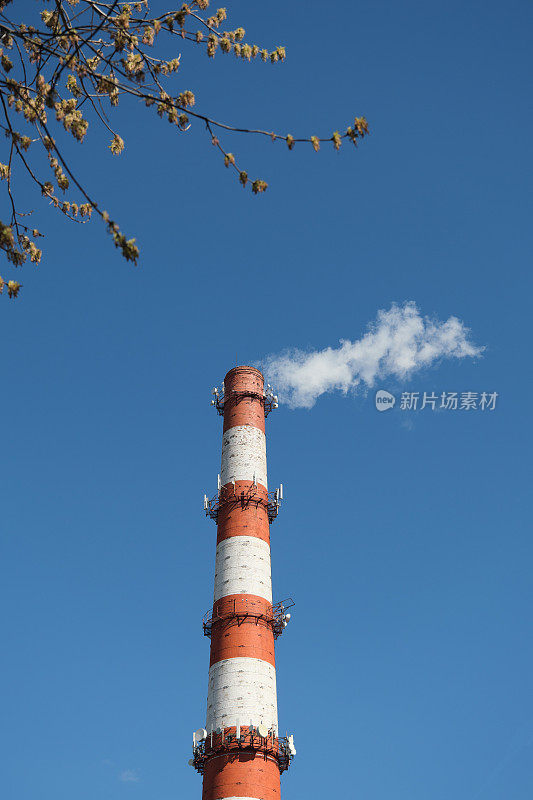 工业烟囱里冒出的滚滚浓烟随风飘过晴朗的天空