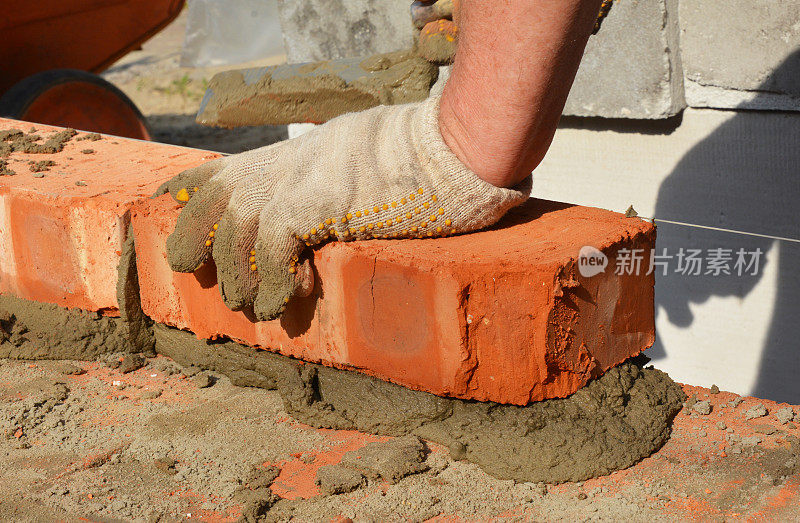 砌筑施工。砌砖工人在砂浆上砌砖，用抹刀、线或水平线砌成砖墙的水平面。