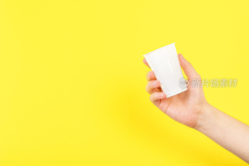 手拿一次性塑料杯，黄色背景