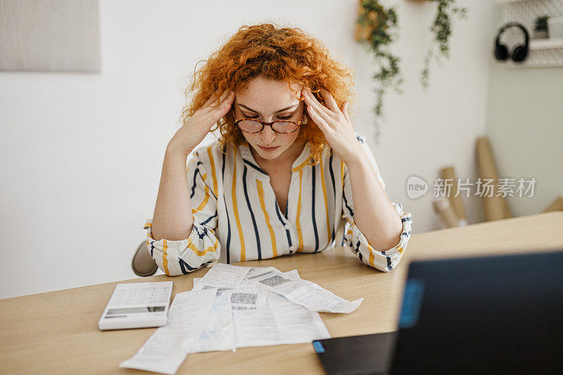 画像一个年轻的成年妇女在家里检查她的能源账单，坐在她的家庭办公室。她有一种忧虑的表情