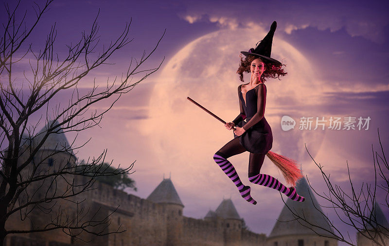 一名芭蕾舞女演员穿着黑女巫服装，头戴帽子，骑在扫帚上，以一座古老的城堡和一个巨大的紫丁香月亮为背景，在空中飞翔。芭蕾在万圣节。