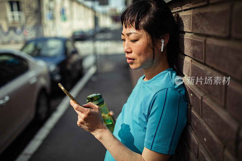 一名年轻的日本女子在健身后使用智能手机休息