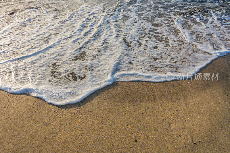 海浪与白色泡沫在细沙从海滩在埃及日出期间的细节
