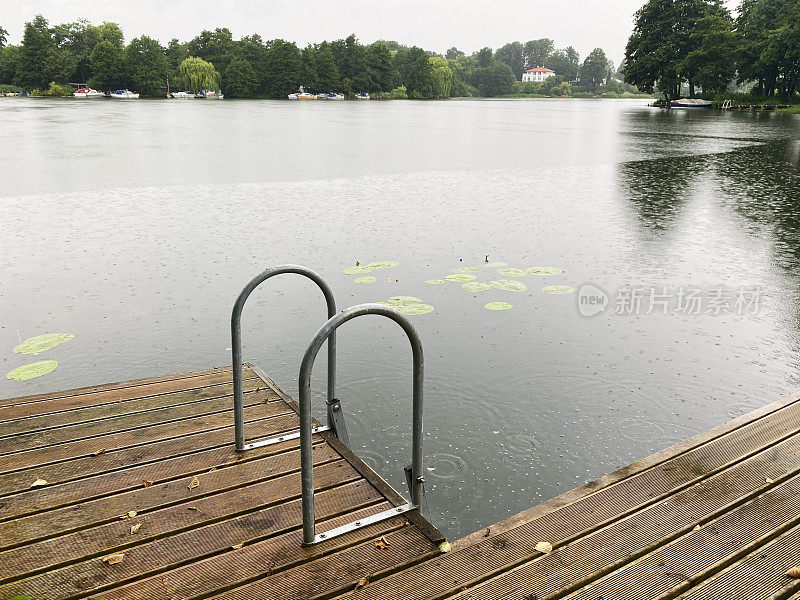 下雨天在斯堪的那维亚湖的梯子上游泳